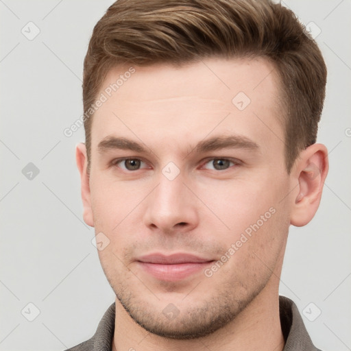 Joyful white young-adult male with short  brown hair and grey eyes