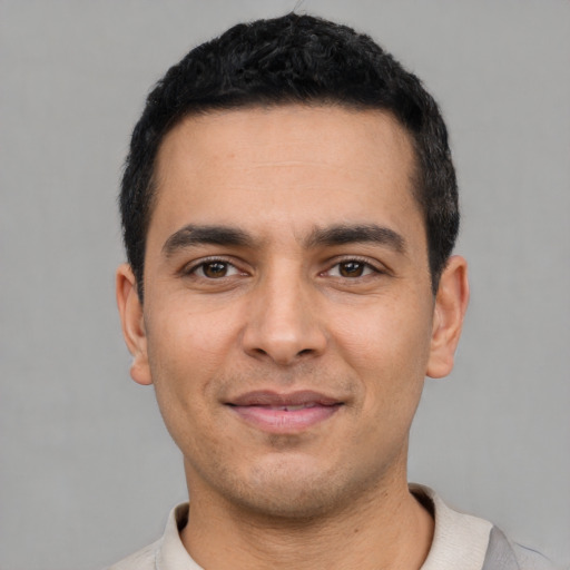 Joyful latino young-adult male with short  black hair and brown eyes