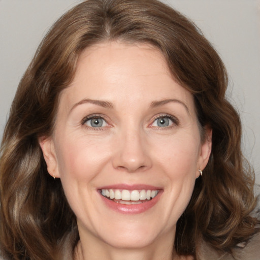 Joyful white adult female with medium  brown hair and grey eyes