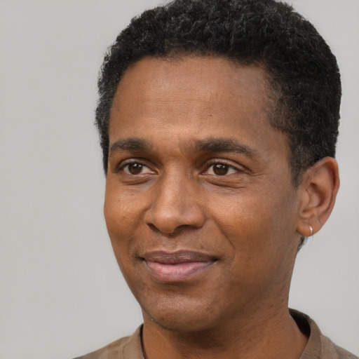 Joyful black young-adult male with short  black hair and brown eyes