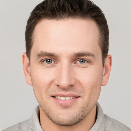 Joyful white young-adult male with short  brown hair and grey eyes