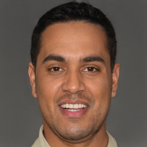 Joyful latino young-adult male with short  black hair and brown eyes