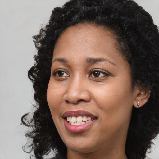 Joyful black young-adult female with long  black hair and brown eyes