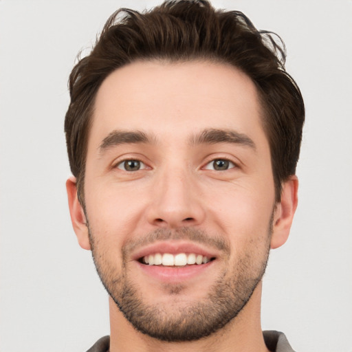 Joyful white young-adult male with short  brown hair and grey eyes