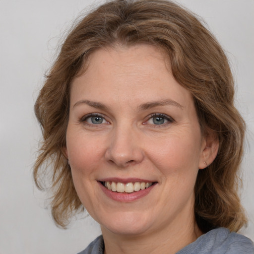 Joyful white adult female with medium  brown hair and grey eyes