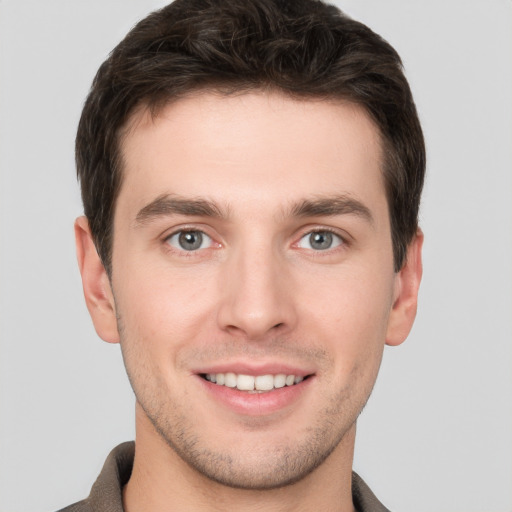 Joyful white young-adult male with short  brown hair and grey eyes