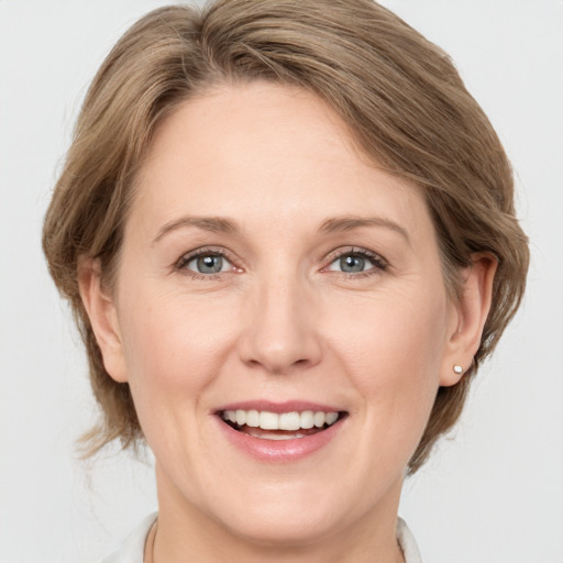 Joyful white adult female with medium  brown hair and grey eyes