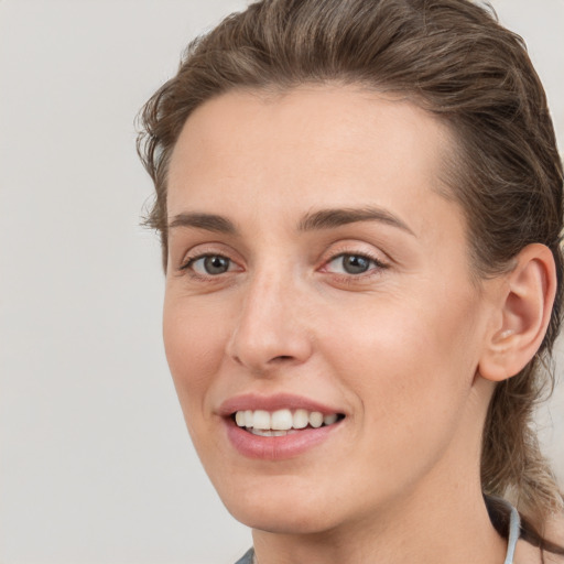 Joyful white young-adult female with medium  brown hair and grey eyes