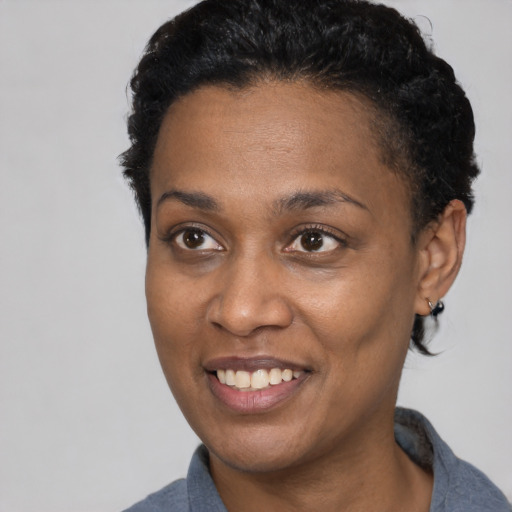 Joyful black adult female with short  black hair and brown eyes