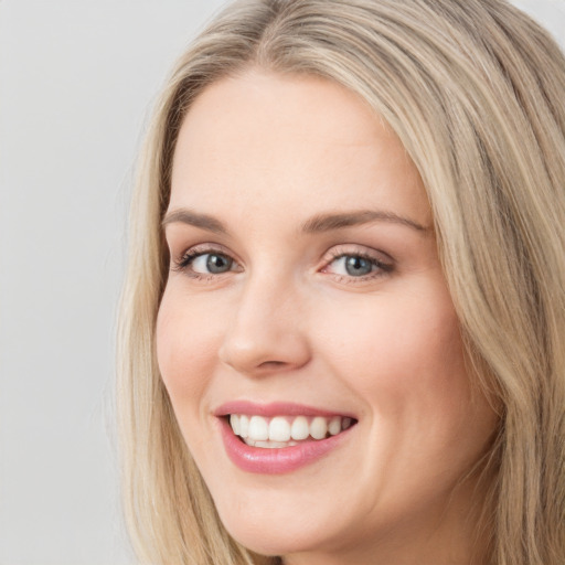 Joyful white young-adult female with long  brown hair and blue eyes