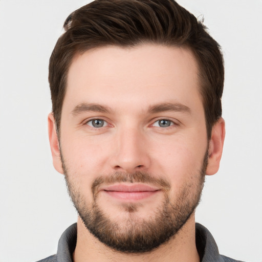 Joyful white young-adult male with short  brown hair and grey eyes