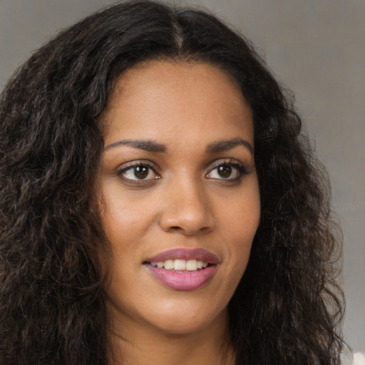 Joyful black young-adult female with long  brown hair and brown eyes