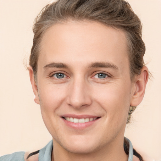 Joyful white young-adult male with short  brown hair and grey eyes