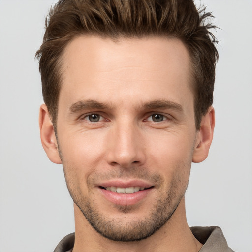 Joyful white young-adult male with short  brown hair and grey eyes