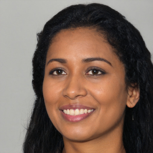 Joyful black young-adult female with long  black hair and brown eyes
