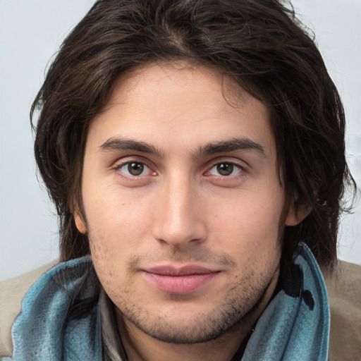 Joyful white young-adult male with long  brown hair and brown eyes