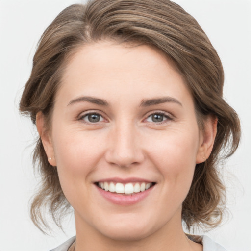 Joyful white young-adult female with medium  brown hair and grey eyes