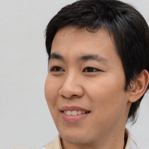 Joyful asian young-adult male with medium  brown hair and brown eyes
