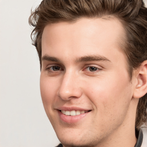 Joyful white young-adult male with medium  brown hair and grey eyes