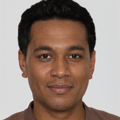 Joyful black young-adult male with short  black hair and brown eyes