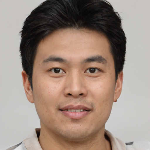 Joyful asian young-adult male with short  brown hair and brown eyes