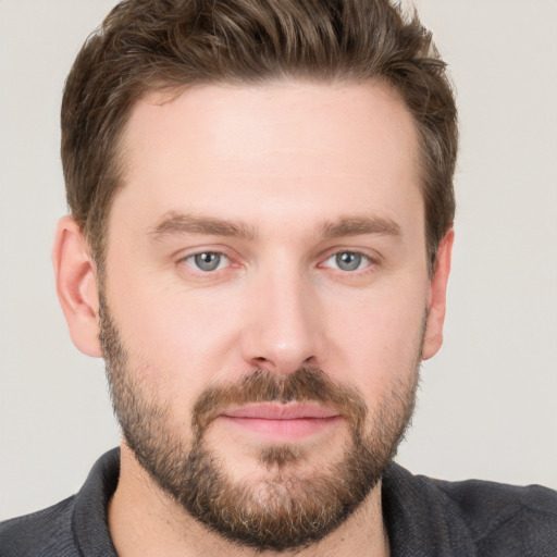 Joyful white young-adult male with short  brown hair and grey eyes