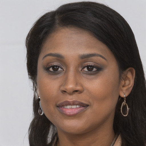 Joyful black young-adult female with long  brown hair and brown eyes