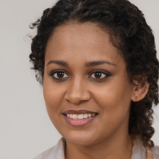 Joyful black young-adult female with medium  brown hair and brown eyes