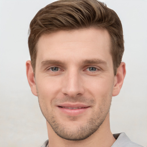 Joyful white young-adult male with short  brown hair and grey eyes