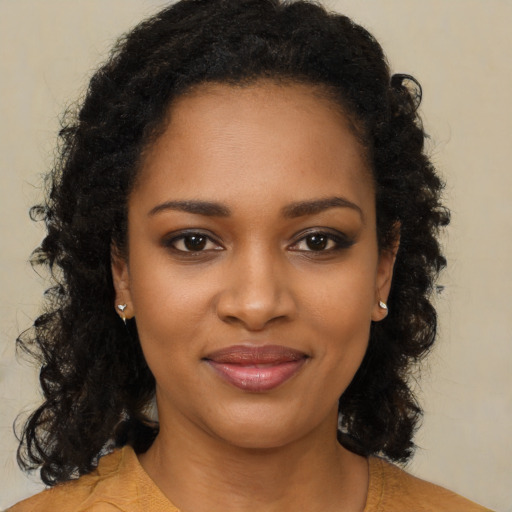 Joyful black young-adult female with long  brown hair and brown eyes