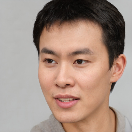 Joyful asian young-adult male with short  brown hair and brown eyes