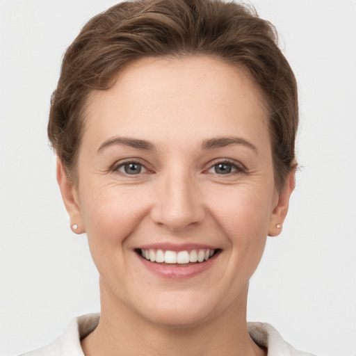 Joyful white young-adult female with short  brown hair and grey eyes