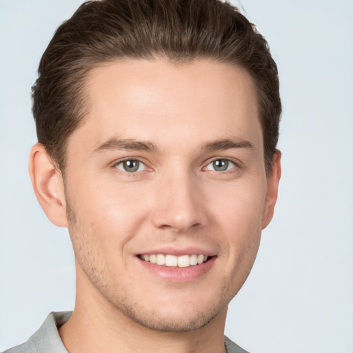 Joyful white young-adult male with short  brown hair and grey eyes