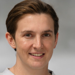 Joyful white young-adult male with short  brown hair and grey eyes