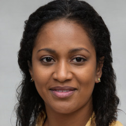 Joyful black young-adult female with long  brown hair and brown eyes