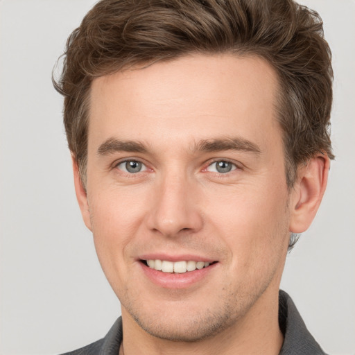 Joyful white young-adult male with short  brown hair and grey eyes