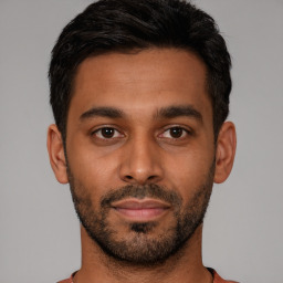 Joyful latino young-adult male with short  black hair and brown eyes