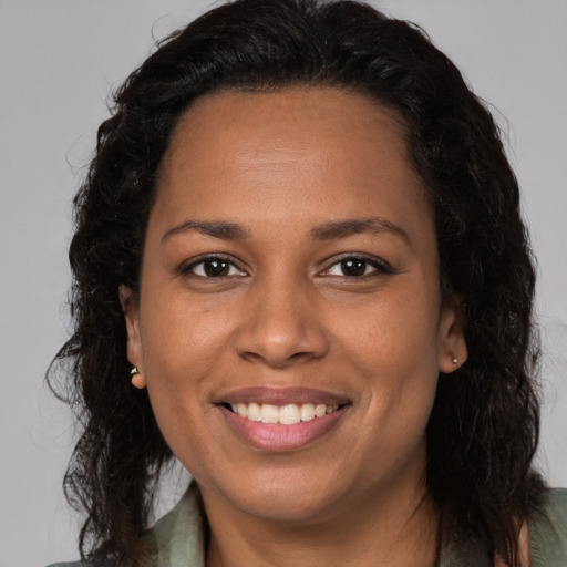 Joyful black adult female with long  brown hair and brown eyes