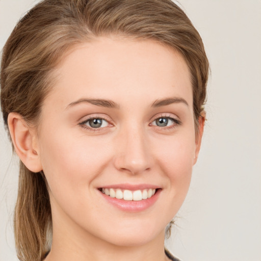 Joyful white young-adult female with medium  brown hair and grey eyes