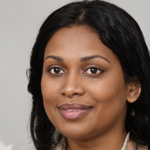 Joyful black young-adult female with long  black hair and brown eyes