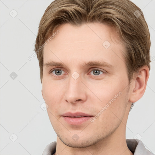 Joyful white young-adult male with short  brown hair and grey eyes