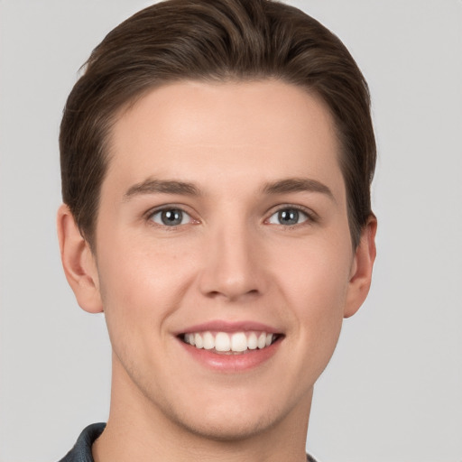 Joyful white young-adult male with short  brown hair and grey eyes