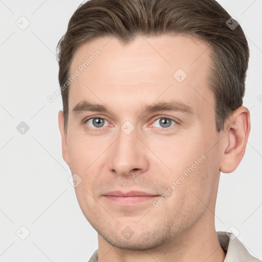 Joyful white young-adult male with short  brown hair and grey eyes