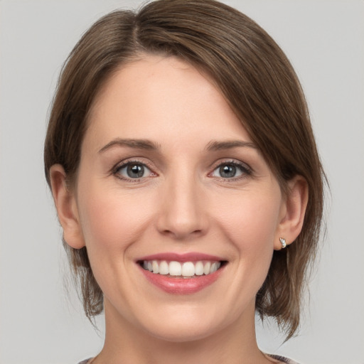 Joyful white young-adult female with medium  brown hair and grey eyes