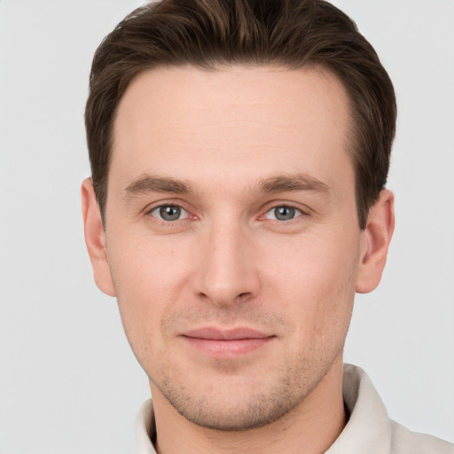 Joyful white young-adult male with short  brown hair and grey eyes