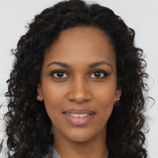 Joyful black young-adult female with long  brown hair and brown eyes