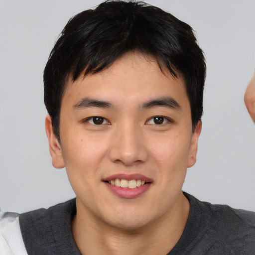 Joyful asian young-adult male with short  black hair and brown eyes