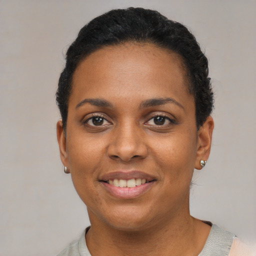 Joyful black young-adult female with short  black hair and brown eyes
