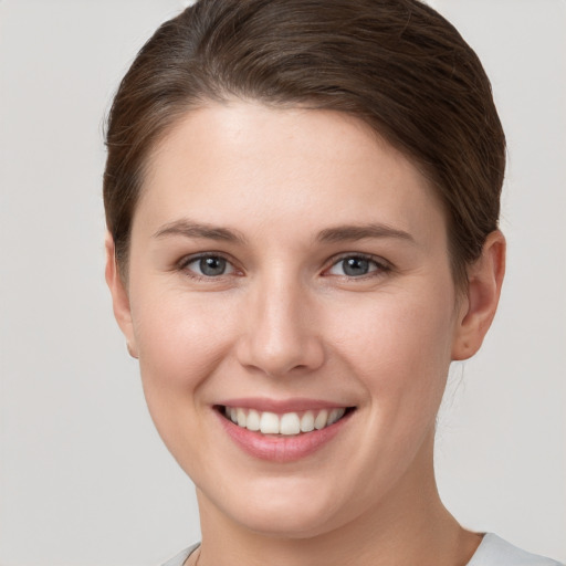 Joyful white young-adult female with short  brown hair and grey eyes