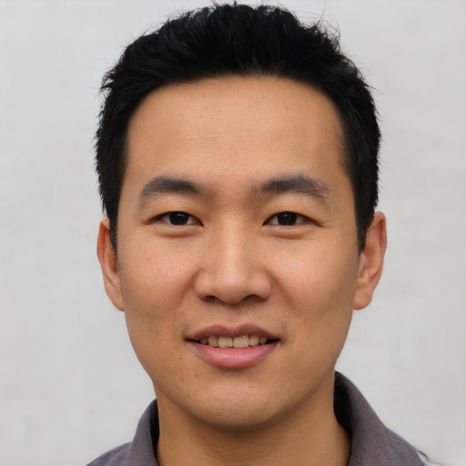 Joyful asian young-adult male with short  black hair and brown eyes
